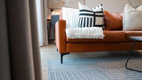a living room with an orange couch with pillows on it at Luxury Apartment at Ellipse Waterfall, Midrand Near Mall of Africa in Midrand