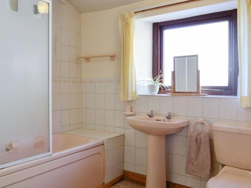 a bathroom with a sink and a toilet and a window at Swallows Return in Whitehaven