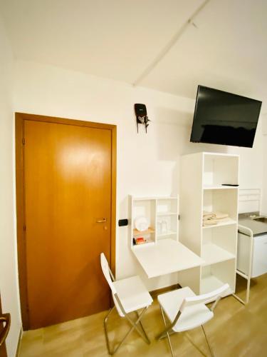 um quarto com duas cadeiras brancas e uma porta castanha em Petite room em Noicattaro