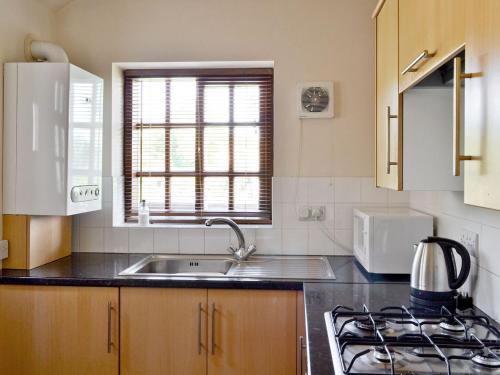 a kitchen with a sink and a stove and a window at Chestnut Cottage in Ebberston