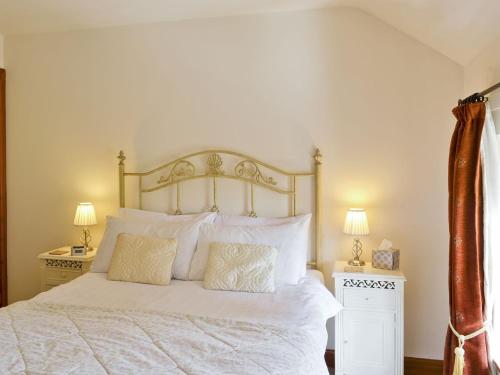 a bedroom with a bed with white sheets and pillows at Chestnut Cottage in Ebberston