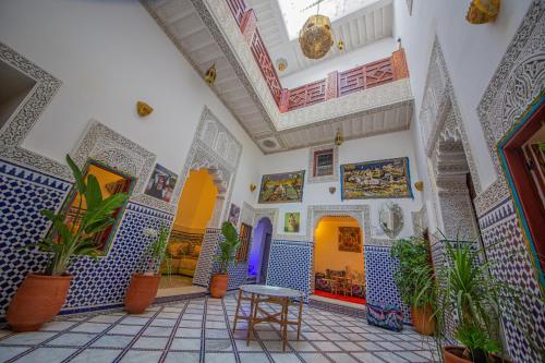 Zimmer mit blauen und weißen Fliesen und Pflanzen in der Unterkunft Riad Rayhana in Fès