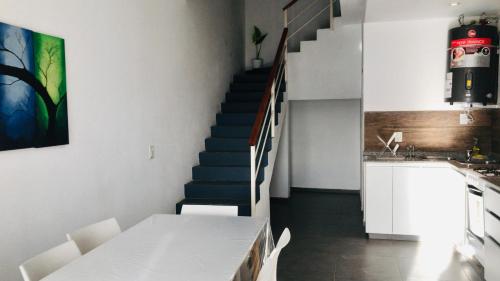 una cocina con una escalera con una mesa y sillas blancas en Lofts en la Sierra!! en Villa Carlos Paz