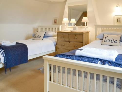 two beds in a white room with love pillows at Apple Tree Cottage in Foulsham