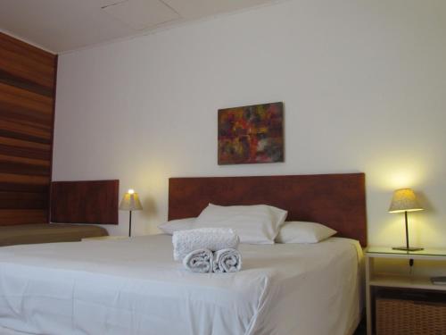 1 dormitorio con 1 cama blanca y 2 toallas en Pousada La Vivienda, en Santana do Livramento
