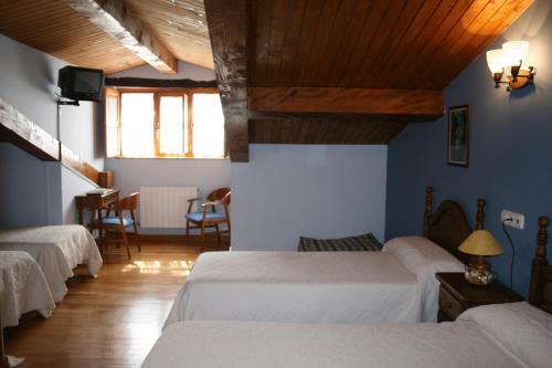 a bedroom with three beds and a table and chairs at Posada Los Vallucos in San Martín de Elines
