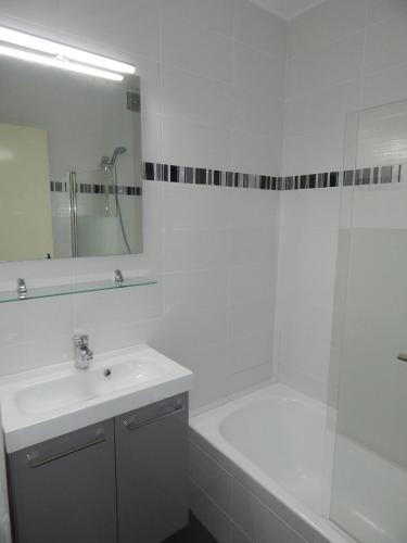 La salle de bains blanche est pourvue d'une baignoire, d'un lavabo et d'une douche. dans l'établissement Pied de Piste à 20 M du telesiege 