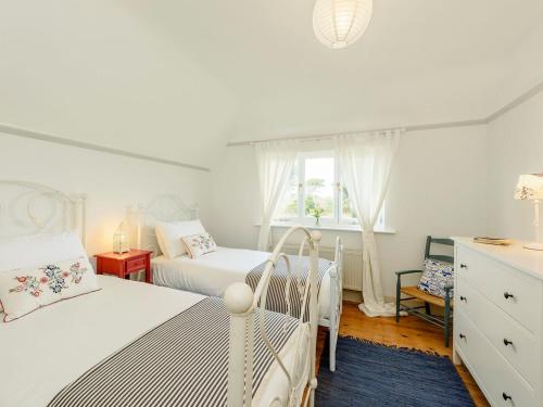 a white bedroom with two beds and a window at The Jays in Selsey