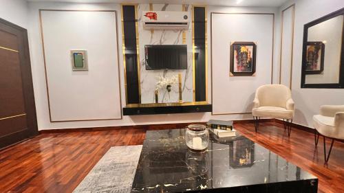 a living room with a tv and a glass table at Grand Atrium Designer Apartment in Faisalabad