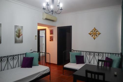 una sala de estar con dos camas y una mesa en Apartamentos Turisticos Casa Cantillo, en Carmona