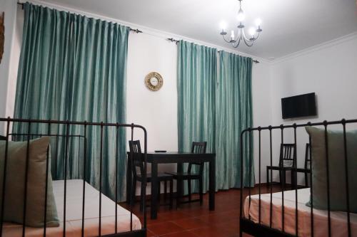 1 dormitorio con cortinas verdes, mesa y sillas en Apartamentos Turisticos Casa Cantillo, en Carmona