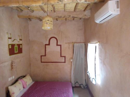 Cette petite chambre comprend un lit et une fenêtre. dans l'établissement Auberge Restaurant TISSILI " Oasis de Fint", à Fint