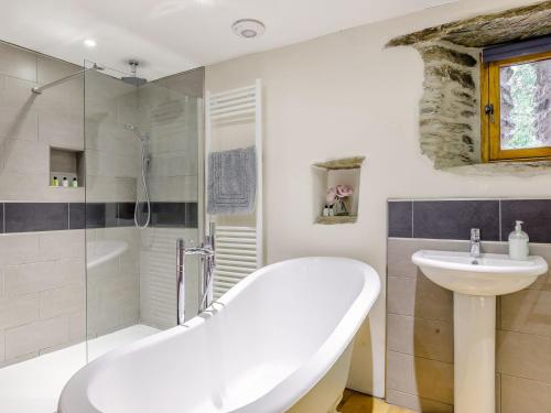 La salle de bains blanche est pourvue d'une baignoire et d'un lavabo. dans l'établissement The Threshing Barn - Hssw, à East Down