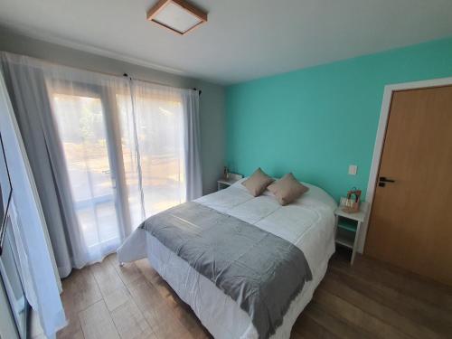 a bedroom with a bed with blue walls and a window at Hygge Haus in Villa La Angostura