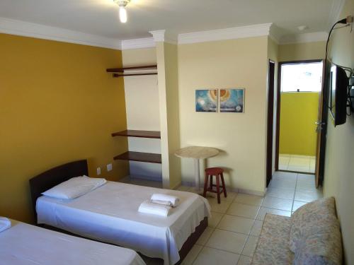 Cette chambre comprend deux lits, une table et une chaise. dans l'établissement Hospedaria Lua Raio de Sol, à Natal