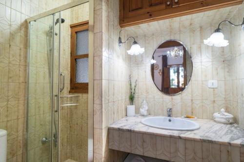 ein Bad mit einem Waschbecken und einer Glasdusche in der Unterkunft El jardín del botánico in Hinojos