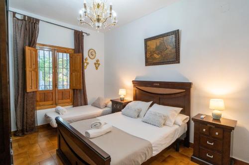 1 dormitorio con 2 camas y lámpara de araña en El jardín del botánico en Hinojos
