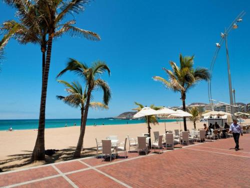 uma praia com cadeiras e palmeiras e o oceano em Coqueto apartamento a 50 metros de la playa em Las Palmas de Gran Canaria