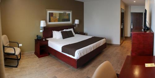 a bedroom with a large bed and a chair at Best Western Bazarell Inn in Montemorelos