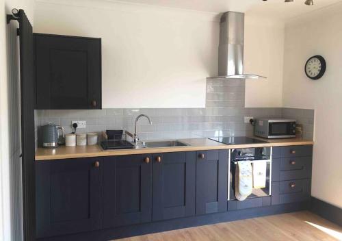 Una cocina con gabinetes azules y un fregadero. en Little Oaks, en Pembrokeshire
