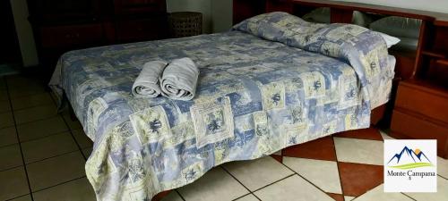 a bed with a blue comforter and towels on it at Hotel Monte Campana Heredia in Birrí
