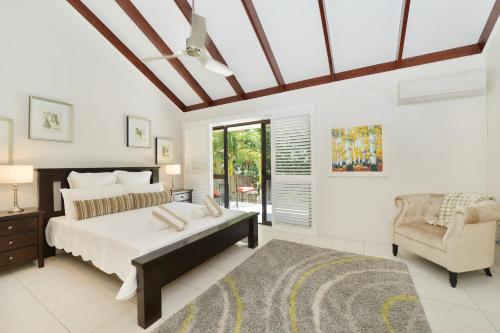a bedroom with a large bed and a chair at Sea La Villa Port Douglas in Port Douglas
