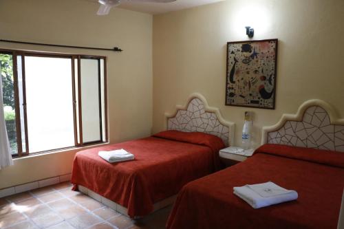 una camera con due letti con lenzuola rosse e una finestra di Hotel Carrizal Spa a Apazapan