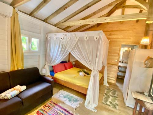 una camera da letto con un letto a baldacchino di Villa Gaïa - Bungalow Ti-Spa et son jacuzzi privé dans un jardin tropical, séjour en amoureux ou en famille a Le Diamant
