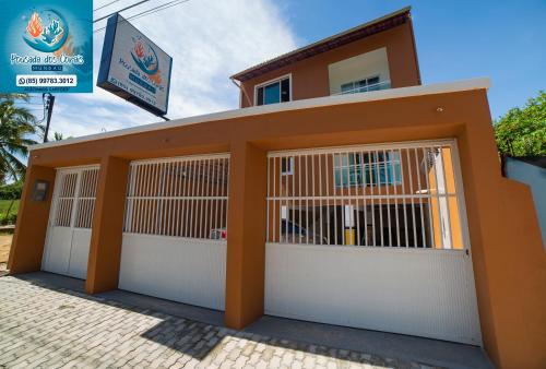 un edificio con cuatro puertas de garaje y un cartel en Pousada dos Corais, en Mundaú