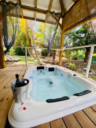 a jacuzzi tub sitting on a wooden deck at Villa Gaïa - Bungalow Ti-Spa et son jacuzzi privé dans un jardin tropical, séjour en amoureux ou en famille in Le Diamant