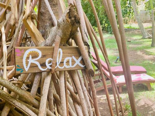 a sign that says relax on a tree with a bench at Villa Gaïa - Bungalow Ti-Spa et son jacuzzi privé dans un jardin tropical, séjour en amoureux ou en famille in Le Diamant