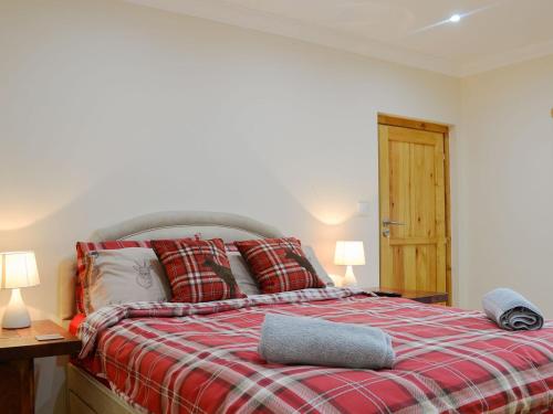 um quarto com uma cama com um cobertor xadrez vermelho em Smiddy Bothy em Edzell