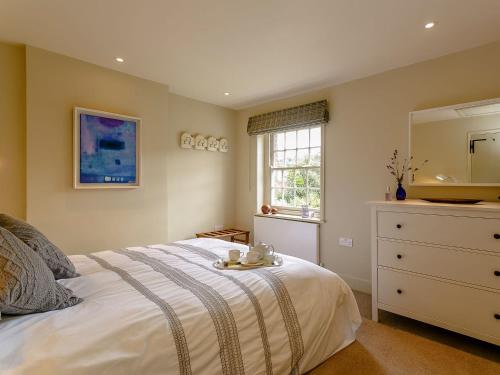 a bedroom with a bed with a dresser and a mirror at Rose Cottage in Poynings
