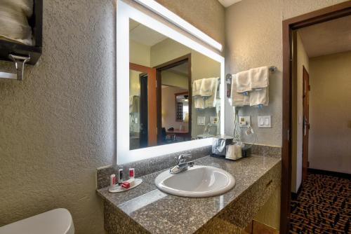 a bathroom with a sink and a mirror and a toilet at Ramada by Wyndham Oklahoma City Airport North in Oklahoma City