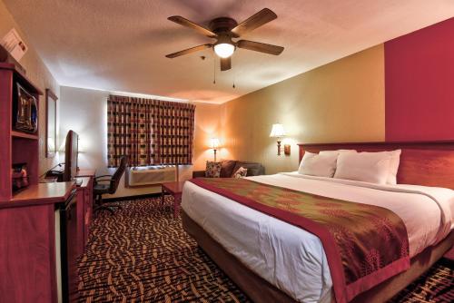 Ramada by Wyndham Oklahoma City Airport North في مدينة اوكلاهوما: غرفة الفندق بسرير ومروحة سقف