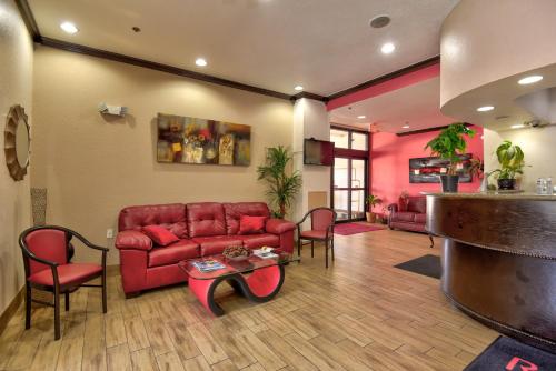 a living room with a red couch and chairs at Ramada by Wyndham Oklahoma City Airport North in Oklahoma City