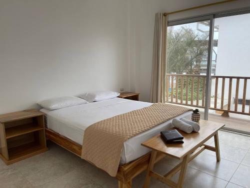 a bedroom with a bed with a table and a balcony at Samana Hostal, Puerto Engabao in Engabao