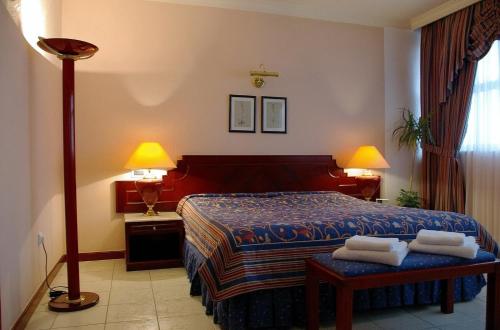 1 dormitorio con 1 cama, 2 lámparas y mesa en Bellevue Hotel and Resort, en Bardejov