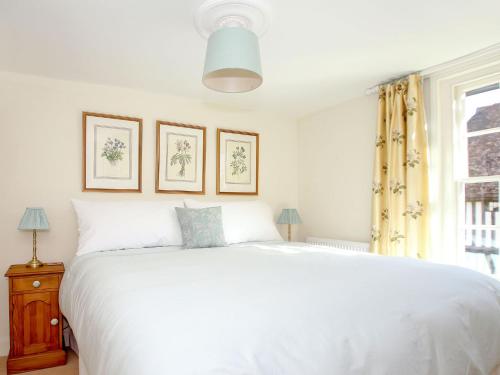 a bedroom with a large white bed and a window at Pilgrim Cottage in Hollingbourne