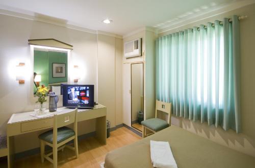 a hotel room with a bed and a desk and a television at New Dawn Pensionne House in Cagayan de Oro
