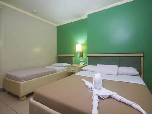two beds in a room with green walls at New Dawn Pensionne House in Cagayan de Oro