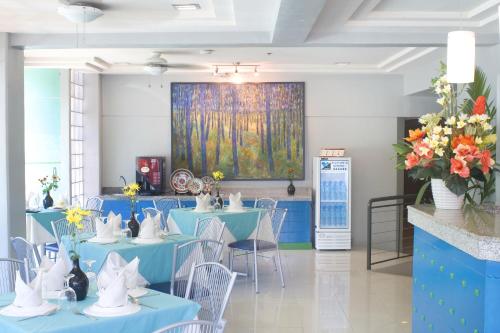 a room with blue tables and chairs and a painting at New Dawn Pensionne House in Cagayan de Oro