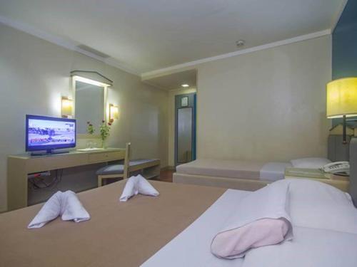 a bedroom with a bed and a desk and a television at New Dawn Pensionne House in Cagayan de Oro