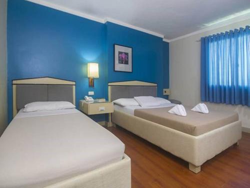 two beds in a room with blue walls at New Dawn Pensionne House in Cagayan de Oro