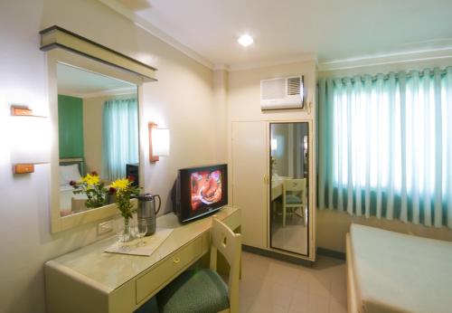 a room with a vanity with a tv and a mirror at New Dawn Pensionne House in Cagayan de Oro