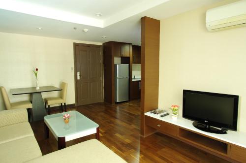 a living room with a couch and a tv and a table at The Ninth Place Serviced Residence in Bangna