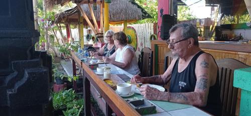 un groupe de personnes assises à une table dans l'établissement Khrisna Sunrise Homestay Tulamben, à Tulamben