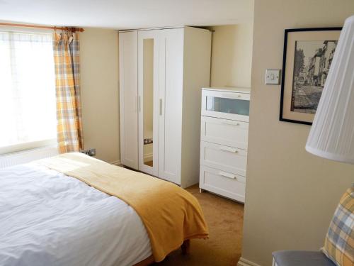 a bedroom with a bed and a dresser at Nelson Steps 3 in Kingswear