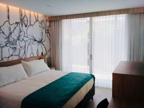 梅爾加的住宿－Hotel Karmel，卧室配有一张挂着花壁画的床。