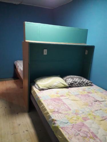 een slaapkamer met een bed met een groen hoofdeinde bij cantinho bom in Ubatuba